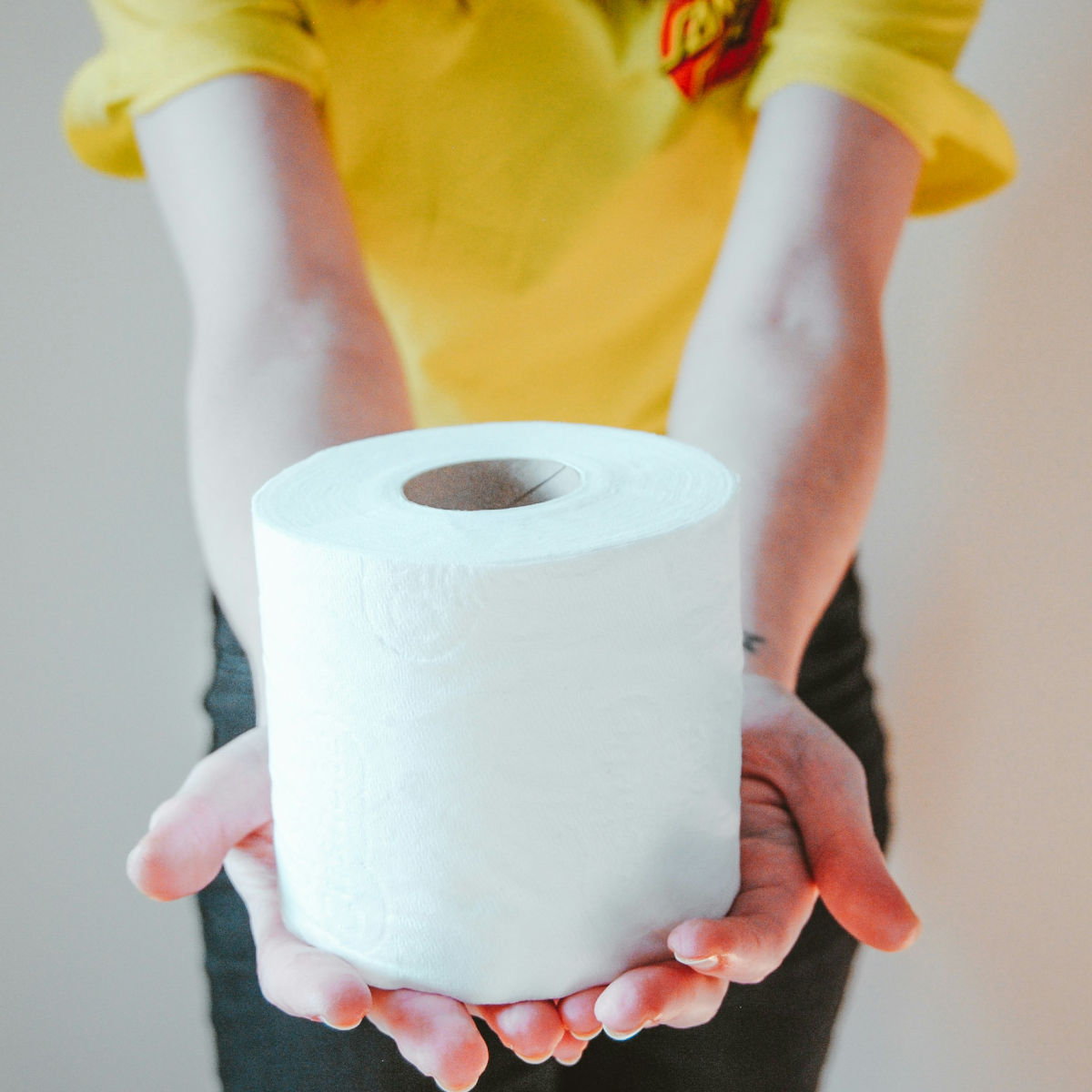 En tjej som sträcker sig fram med den sista toarullen. Den sista rullen används med en helt annan försiktighet innan förrådet fylls på igen